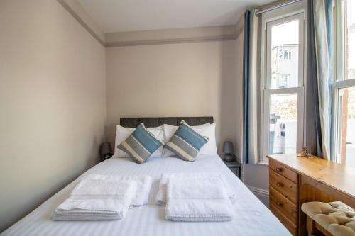 Un dormitorio con una cama con dos almohadas y una ventana. en Sea La Vie- Cosy, Modern, Harbourside Views, en Brixham