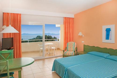 a bedroom with a bed and a table and a balcony at Iberostar Ciudad Blanca in Port d'Alcudia