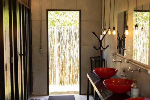 uma casa de banho com tigelas vermelhas num balcão com uma porta em Eco Hostel & Suítes em São Miguel do Gostoso