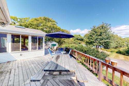 a wooden deck with a bench and an umbrella at Murray Hill Waterside in East Boothbay