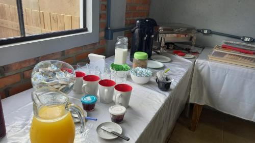 una mesa con un mantel blanco con tazas y bebidas en Pousada Moçamba Dunas Beach, en Florianópolis