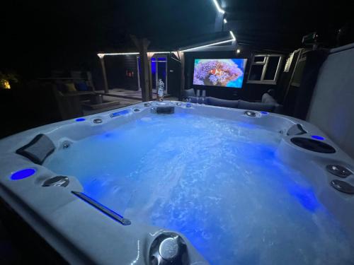 a jacuzzi tub with a tv in a room at Hot tub, 110Inch Outdoor Cinema, Fire Pit, 4 Acre garden, Luxury 5 Star Woodland Lodge in Skegness