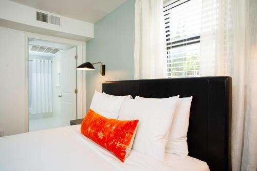 a bedroom with a bed with a red pillow on it at Abode Nashville - Marathon Village Near Downtown in Nashville