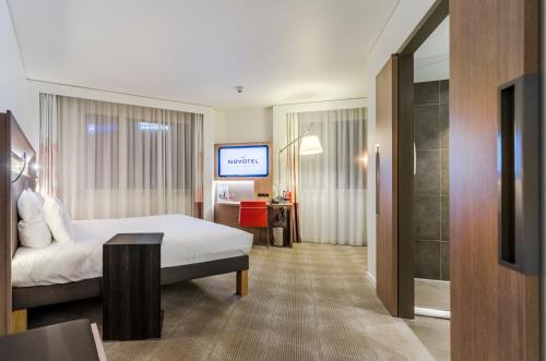 a hotel room with a bed and a television at Novotel Basel City in Basel