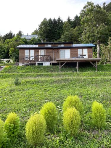 a house in a field with bushes at TOYA LAKEHILL CABIN - The lake view cabin at Lake Toya in Lake Toya