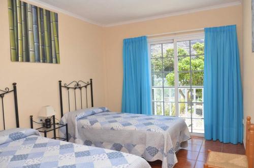 1 dormitorio con 2 camas y una ventana con cortinas azules en Casa Maestro Agustín Nº 2, en Valle Gran Rey