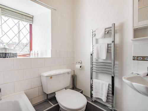 a white bathroom with a toilet and a sink at Halcyon Cottage in Deepcar