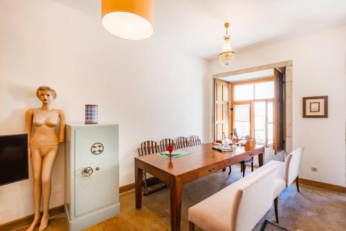 ein Esszimmer mit einem Tisch und einer Statue einer Frau auf einem Kühlschrank in der Unterkunft Atelier by the River in Porto