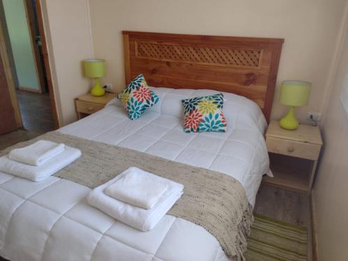 a bedroom with a white bed with two pillows at EL EMBRUJO PATAGON in Coihaique