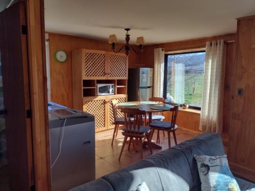 a living room with a couch and a kitchen with a table at EL EMBRUJO PATAGON in Coihaique