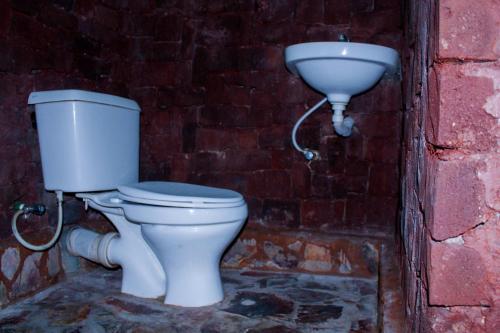 a toilet and a sink in a brick wall at Motel Santaviva in Kisoro