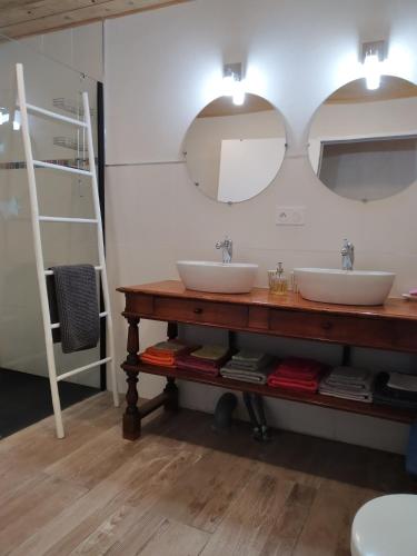 - une salle de bains avec deux lavabos sur une table en bois dans l'établissement Les Troglogîtes, à Brasparts