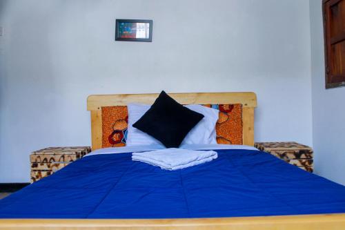 een bed met een blauwe deken en kussens erop bij Motel Santaviva in Kisoro