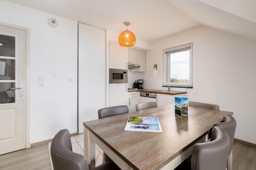 a kitchen and dining room with a wooden table and chairs at Evancy Equihen-Plage in Équihen-Plage