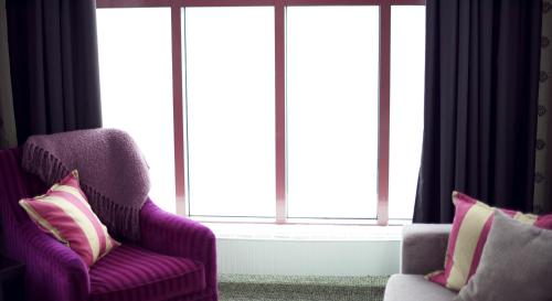 a living room with two chairs and a window at Home Hotel Arcticus in Harstad