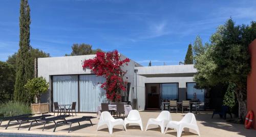 um edifício com cadeiras brancas e flores vermelhas em Chambres d'hôtes VUE MER Mer à 2 min à pied em Sainte-Maxime