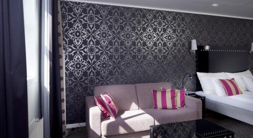 a bedroom with a bed and a couch and a chair at Home Hotel Arcticus in Harstad