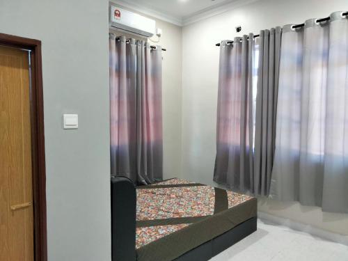 Habitación con cama, cortinas y ventana en Warisan homestay jerteh en Jertih