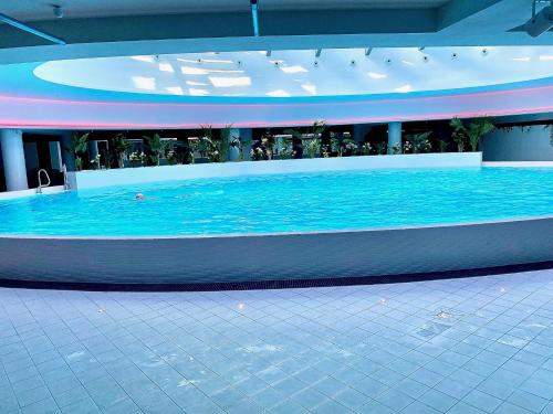 a large pool of blue water in a building at Luksusowy apartament z widokiem, basenem i sauną Hanza Tower Szczecin in Szczecin