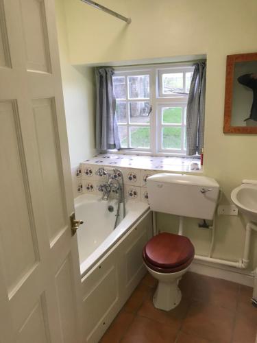 a bathroom with a toilet and a tub and a sink at Beautiful Somerset Cottage with garden views. in Bruton