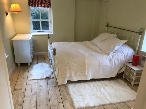 a bedroom with a white bed and a window at Beautiful Somerset Cottage with garden views. in Bruton