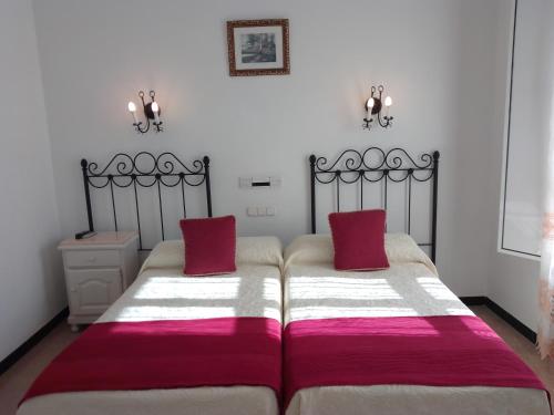a bedroom with two beds with red and white blankets at Hostal 2 estrellas -Restaurante Las Tres Encinas EN EL CENTRO DEL PUEBLO in Cabeza la Vaca