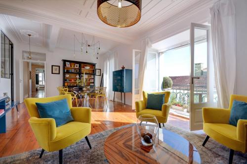 a living room with yellow chairs and a glass table at Magnificent Lisbon Apartment by LovelyStay in Lisbon