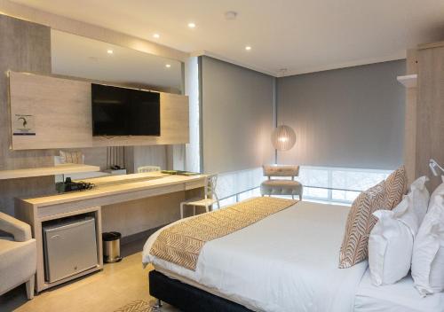 - une chambre avec un lit et un bureau avec une télévision dans l'établissement Hotel Perla Suite, à Santa Marta
