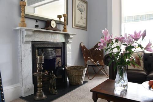 a living room with a fireplace and a table with flowers at Tigh Na Cloich in Pitlochry