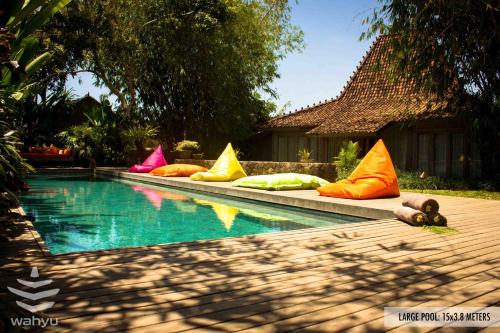 een zwembad met kleurrijke kussens naast een huis bij Wahyu Private Lux Joglo Ideal For Couples W Pool in Seminyak