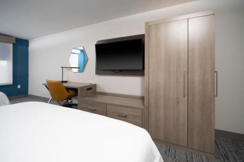 a bedroom with a bed and a cabinet with a television at Holiday Inn Express and Suites Atlanta-Johns Creek by IHG in Johns Creek