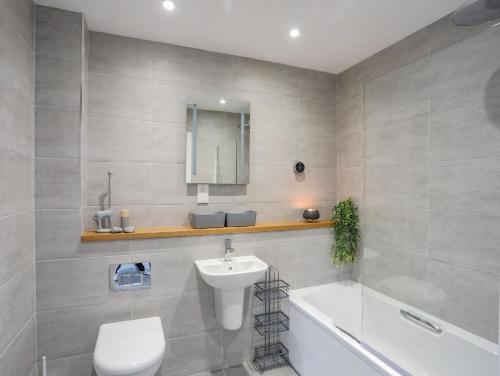 een badkamer met een wastafel, een toilet en een bad bij 9 Lon Y Dryw in Holyhead
