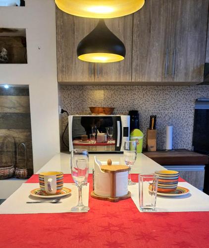 a table with glasses and plates and a microwave at Studio Mirador, todo lo que necesitas para disfrutar in Tarija