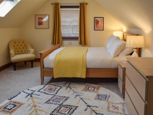 a bedroom with a bed and a chair and a window at Tamarchan Lodge in Ballachulish
