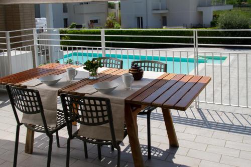 una mesa de madera y sillas en un patio con piscina en Appartamento coorte Brema, en Sirmione