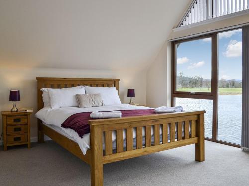 a bedroom with a large bed and a large window at Golf View in Aboyne