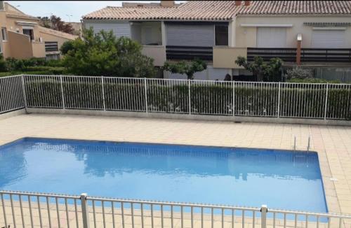 une grande piscine bleue à côté d'une clôture dans l'établissement Cap d'Agde - Résidence Estivales - proche naturiste - Terrasse - Wifi - Parking - Piscine - Clim, au Cap d'Agde