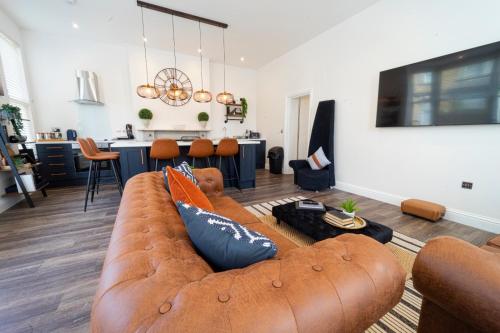 a living room with a brown couch and a kitchen at The Apartment - Brand new, stylish & central in Shanklin