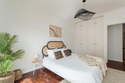 a white bedroom with a bed and a plant at Casa Boma Lisboa - Design & Spacious Apartment With Balcony - Alvalade II in Lisbon
