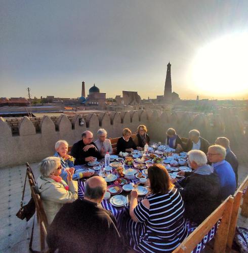 een groep mensen die aan een tafel zitten en eten bij HOTEL KALA KHIVA in Khiva