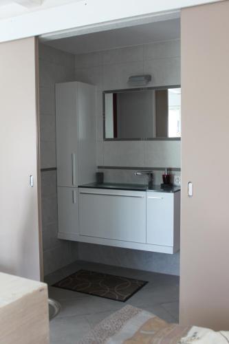 a kitchen with white cabinets and a sink at B&B à la Madeleine in Vétroz