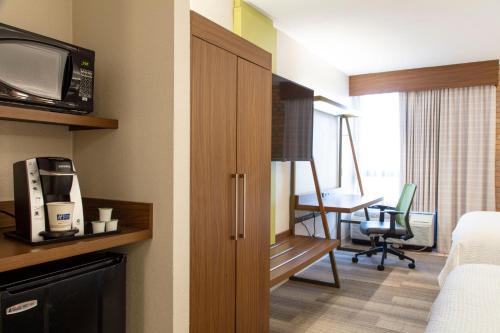 a hotel room with a bed and a desk with a television at Holiday Inn Express - San Antonio Airport by IHG in San Antonio