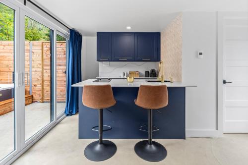a kitchen with a blue island with two bar stools at Les Petits Chalets in Val-des-Lacs