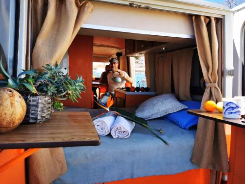 um homem tirando uma foto de uma cama em uma caravana em Rent a BlueClassics 's Campervan combi J9 en Algarve au Portugal em Portimão