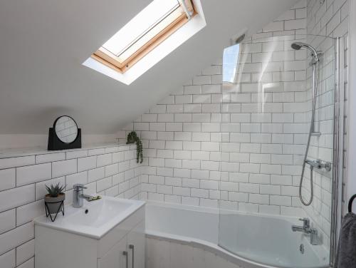 ein Badezimmer mit einem Waschbecken und einer Badewanne in der Unterkunft Lleiniog Cottage in Beaumaris
