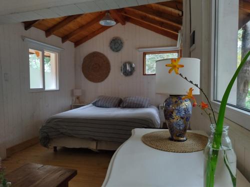 een slaapkamer met een bed en een vaas op een tafel bij Cabañita del bosque in Bariloche