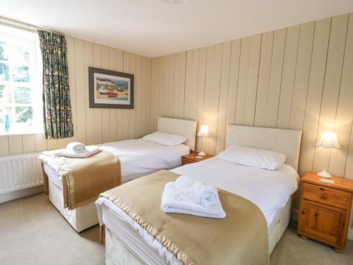 a hotel room with two beds and a window at South Wing Cottage in Yelverton