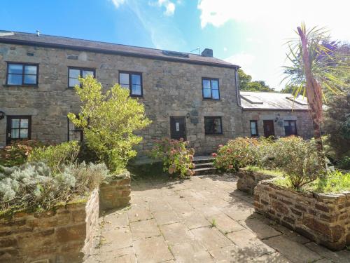an old stone house with a garden in front of it at Barn Cottage in Penzance