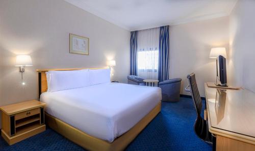 a hotel room with a large white bed and a television at Holiday Inn Yanbu by IHG in Yanbu