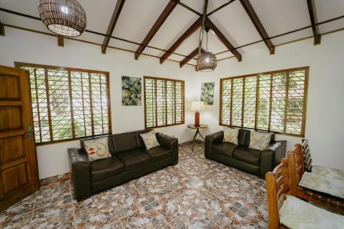 a living room with two leather couches and windows at Dreamy Contentment in Matapalo